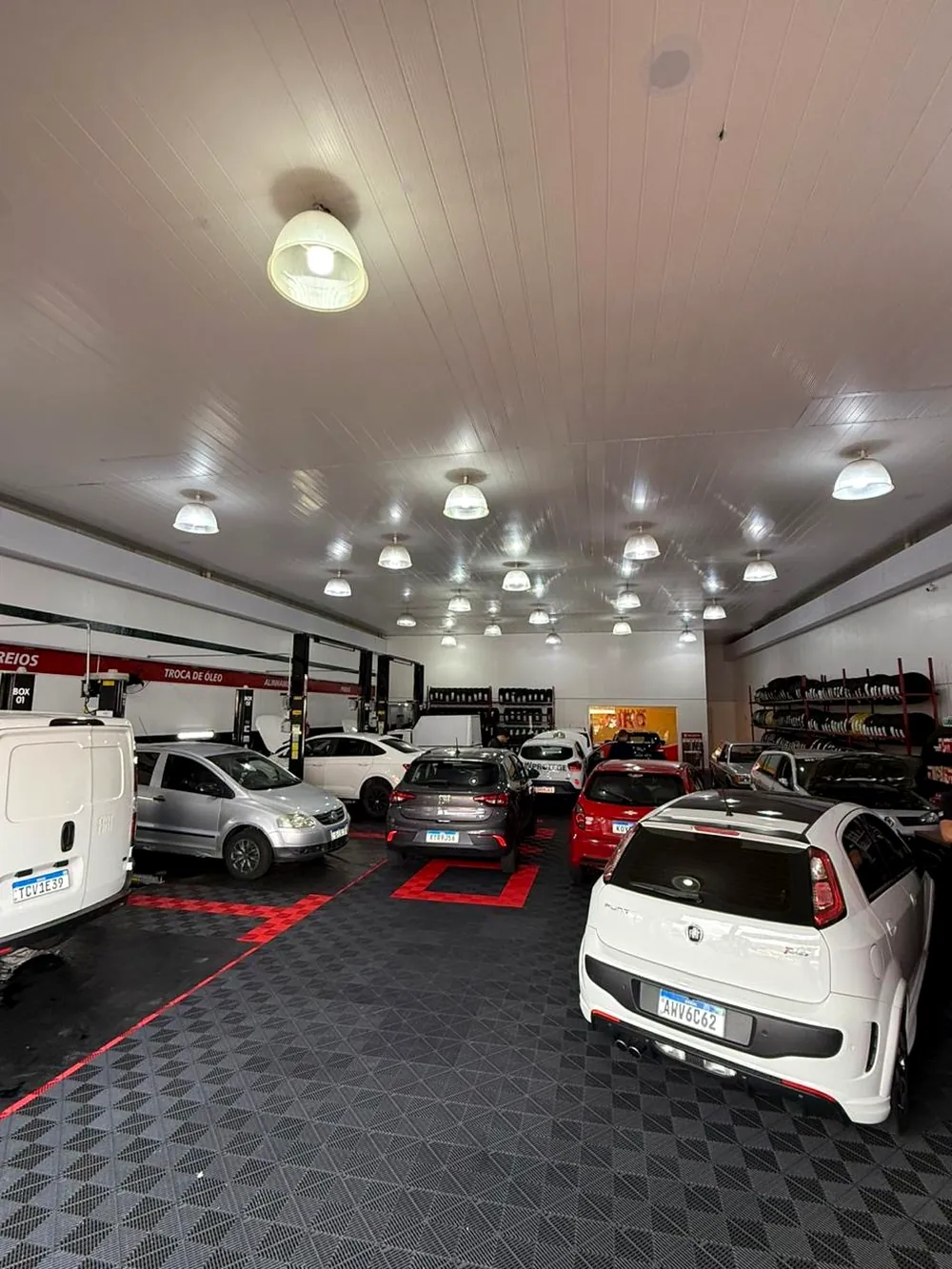 Interior da oficina da Giro Pneus com vários carros em atendimento