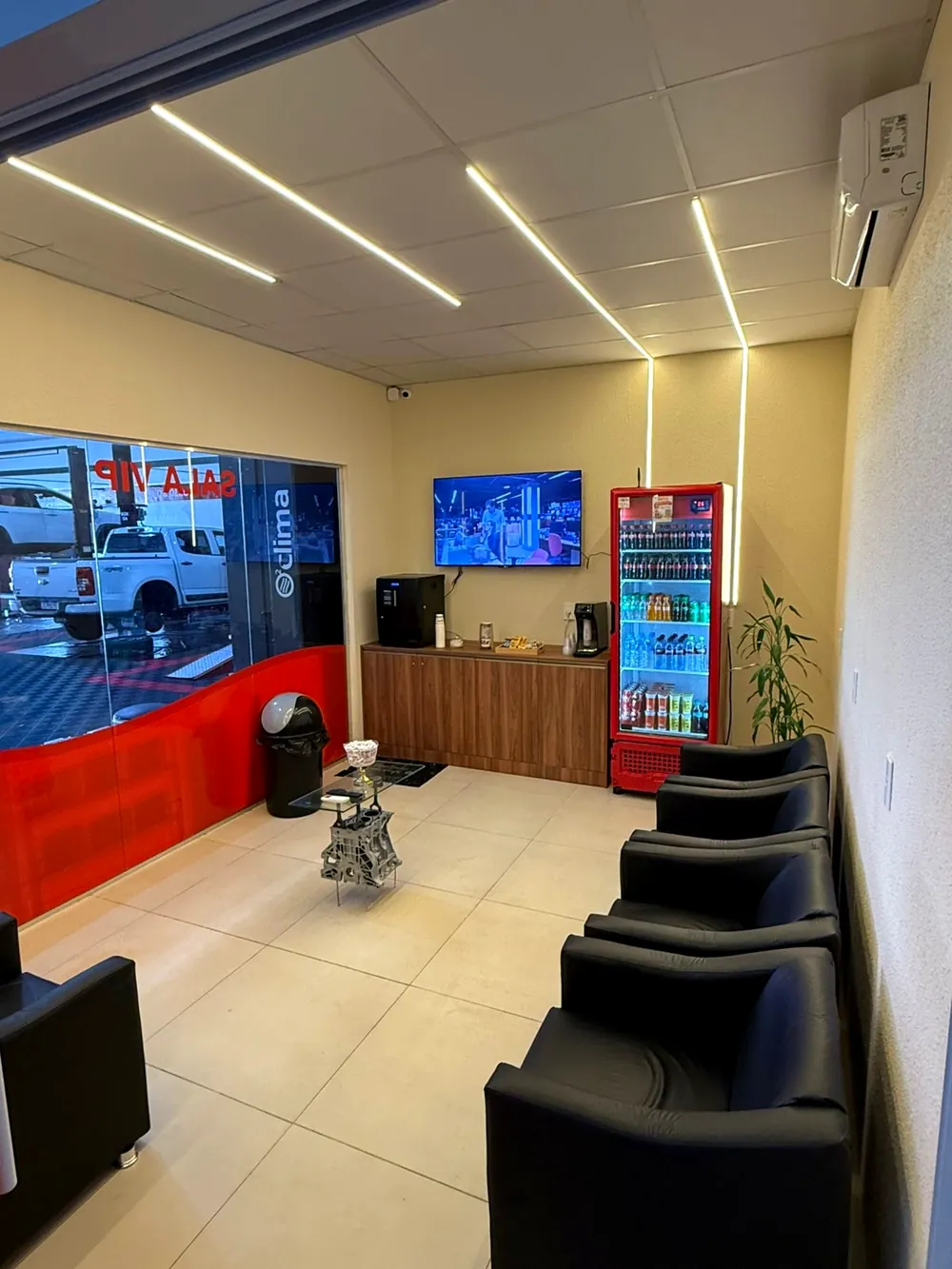Sala de espera VIP da Giro Pneus, com ar-condicionado, TV, café e geladeira de bebidas